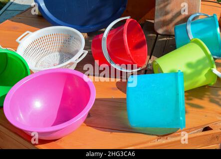 Multicolored empty clean plastic tableware on a wooden background, outdoors, on a sunny summer day. Stock Photo