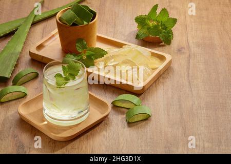 Aloe vera juice in a wooden tray with green leaf , aloe vera in brown wooden background , front view for food and drink advertising Stock Photo