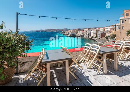 Empty chairs and tables of closed outdoor restaurant with sea view in Greece. Stock Photo