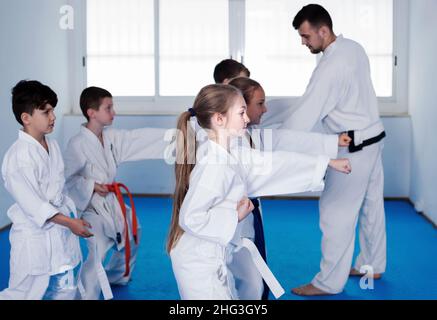 Young children practice karate kicks with coach Stock Photo