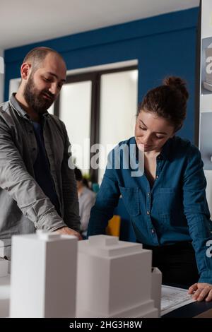 Architect pointing at architectural blueprints collaborating with colleague engineer in modern office. Architects brainstorming ideeas collaborating on construction plans. Stock Photo