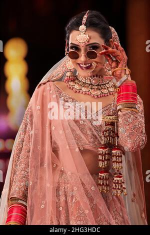 Beautiful Indian bride wearing sunglass during wedding ceremony Stock Photo