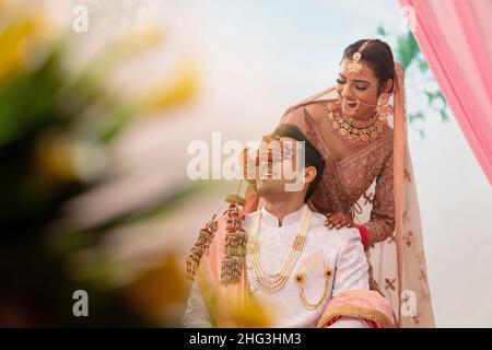 Indian beautiful bride covering her groom's eyes with hands Stock Photo