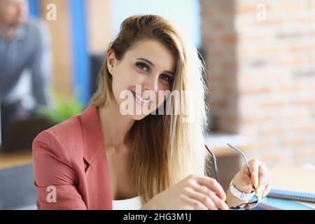 Attractive blonde lady sit in personal cabinet holding glasses Stock Photo