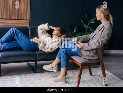 A psychoanalyst in a workshop listens to a patient lying on a couch and talking about her problems. Stock Photo