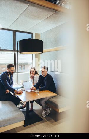 businesspeople looking at a report in a modern co-working space. Three business colleagues having an important meeting. Team of diverse entrepreneurs Stock Photo