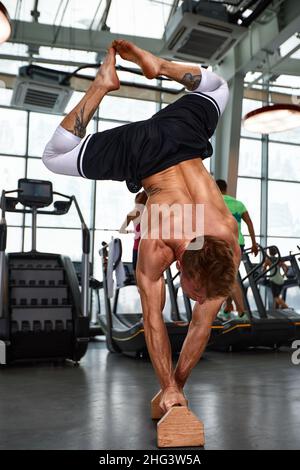 Healthy fitness man doing stretching in the gym using wooden sports equipment. Sport concept, fat burning and a healthy lifestyle Stock Photo