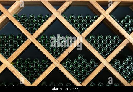 Resting wine bottles stacked on wooden racks in cellar Stock Photo