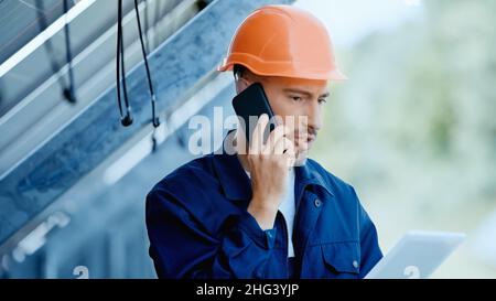 engineer talking on smartphone while holding digital tablet Stock Photo