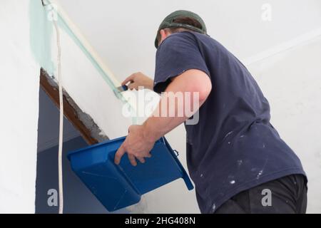 man painting a house wall with a paint Roller. Stock Photo