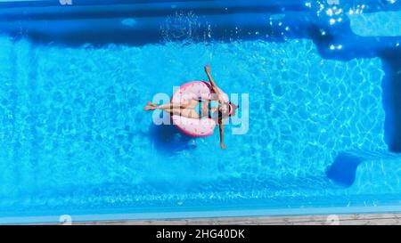 top view of happy woman swimming on inflatable donut in pool Stock Photo