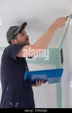 man painting a house wall with a paint Roller. Stock Photo