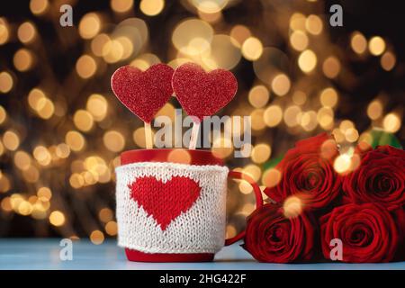 decorative cup with valentines and a bouquet of roses on a festive background. Stock Photo