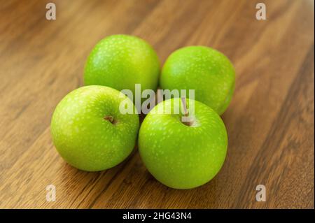 Speckled Granny Smiths apples on wood effect worktop Stock Photo