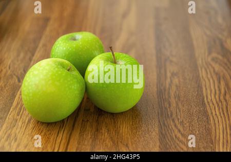 Speckled Granny Smiths apples on wood effect worktop Stock Photo