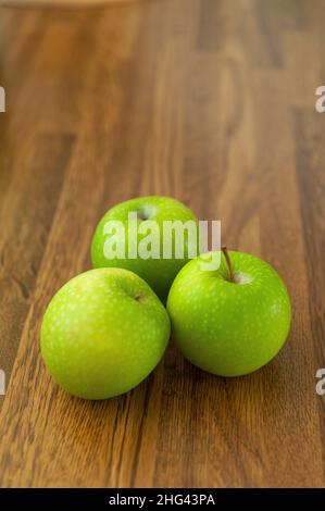 Speckled Granny Smiths apples on wood effect worktop Stock Photo