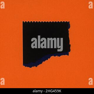 torn orange paper with black hole copy space Stock Photo