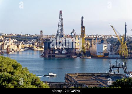 Industrial activity and cranes at docks French Creek, China Dock, Il-Kortin, Grand Harbour, Valletta, Malta. A large drilling platform in The Grand Ha Stock Photo