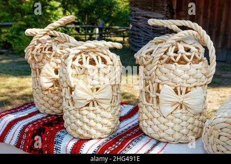 Wicker handbags of round shape made of natural bleached dried corn leaves in the Ukrainian traditional style on an embroidered linen towel. Stock Photo