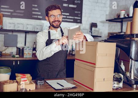 Joyful male worker using tablet computer in cafe Stock Photo