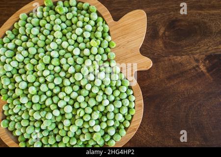 frozen frosty green peas on wooden plate closeup Stock Photo