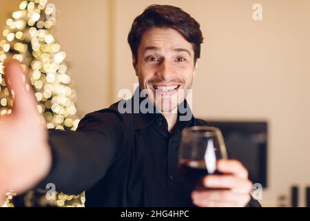 Young man drinking red wine, looking at camera Stock Photo