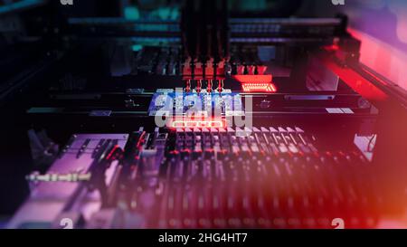 Robotic arm installs electronic components on board. Electronics and Robotics Technology for Chip Production and SMT manufacturing. Computer chips Automatic production by SMT Pick and Place machine. Stock Photo