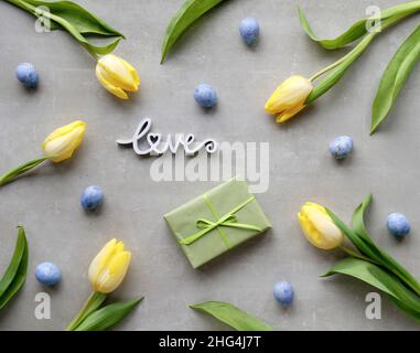 Easter, springtime flat lay with wrapped gift box, yellow tulips and blue quail eggs. Spring holiday background with natural flowers. Easter, Mothers Stock Photo