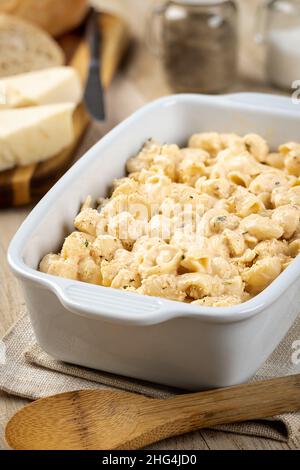 Macaroni and cheese in a white casserole dish on a wooden table Stock Photo