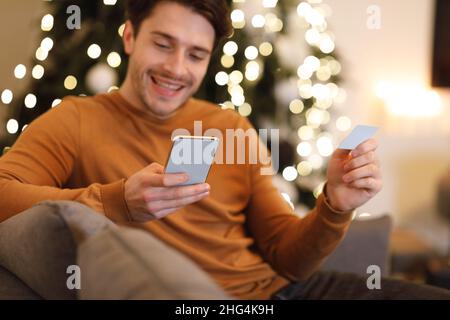 Happy man holding debit credit card, using cellphone Stock Photo