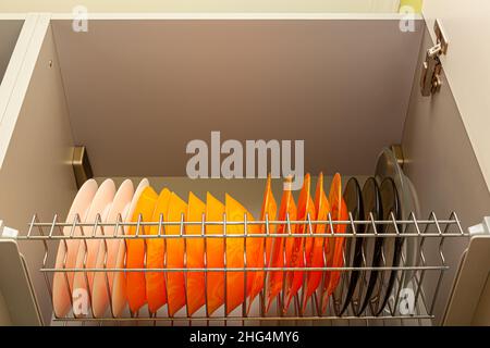 glass plates of different colors stand on a shelf in a kitchen cabinet. High quality photo Stock Photo