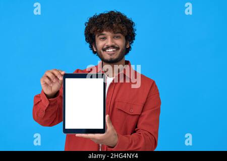 Happy young indian guy showing big mockup tablet screen on blue background. Stock Photo