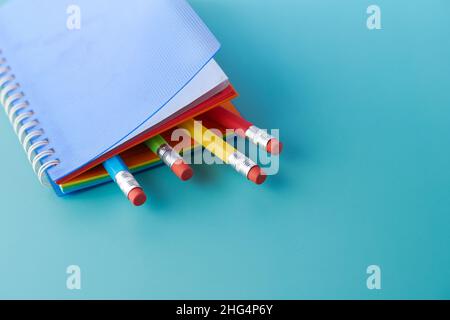 Close up of colorful pencils on notepad on light green background  Stock Photo