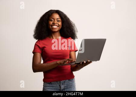 Remote Work. Smiling African American Woman Holding Laptop Computer In Hands Stock Photo