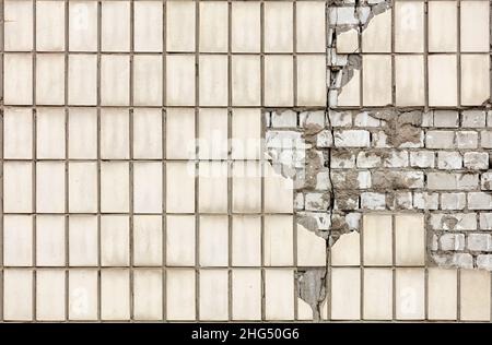 Longitudinal vertical crack on the wall of a house made of silicate brick and lined with rectangular facade tiles. Copy space. Stock Photo