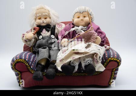 Grandma and Grandpa figurines sit on a couch Stock Photo