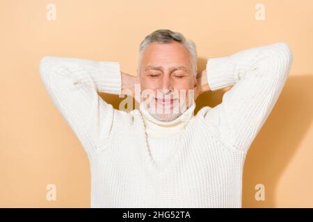 Portrait of attractive dreamy cheerful grey-haired man resting isolated over beige pastel color background Stock Photo