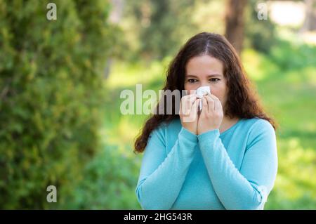 Woman sneezing using a wipe in a park Stock Photo