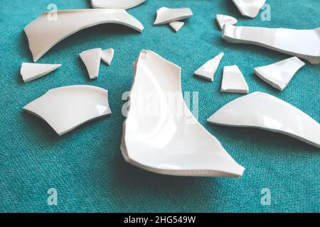 Splinters and Fragments of the broken white ware. Broken Plate, glass.  Pieces of shattered dishes. close-up, side view Stock Photo