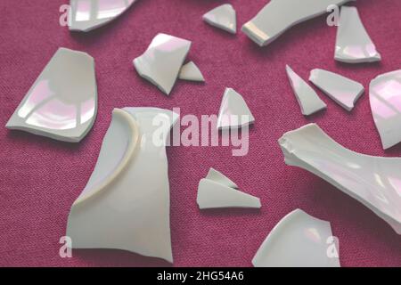 Splinters and Fragments of the broken white ware. Broken Plate, glass.  Pieces of shattered dishes. close-up, top view Stock Photo