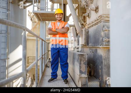 Happy African engineer standing at industrial site Stock Photo