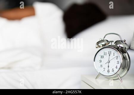 Alarm on bedside over unrecognizable sleeping black lady Stock Photo