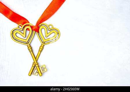 Two vintage keys tied with a red ribbon on a neutral background with copy space. Healthy marriage concept. Stock Photo