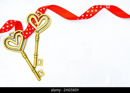 Close-up of two skeleton keys wrapped together with a red dotted ribbon on a neutral background. Romantic Valentine's Day concept. Stock Photo