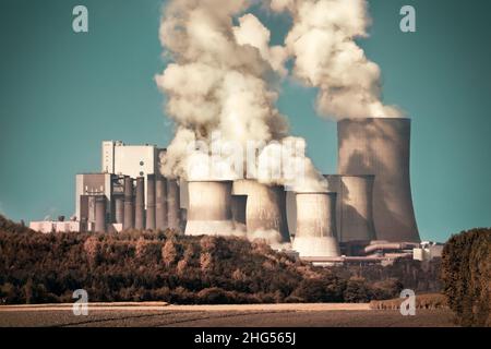 Large coal power plant with steam and smoke on teal sky, dramatic look Stock Photo