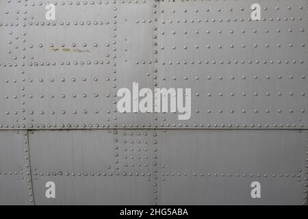 close up of Metal surface of the aircraft fuselage with rivets, Rivets on green or gray metal. Stock Photo