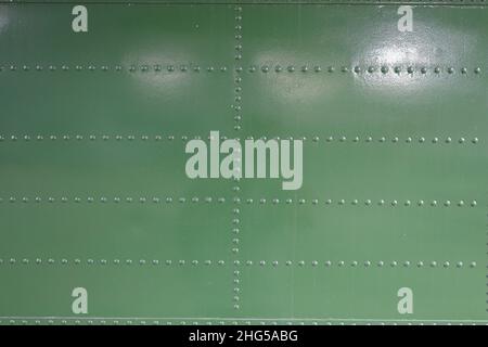 close up of Metal surface of the aircraft fuselage with rivets, Rivets on green or gray metal. Stock Photo