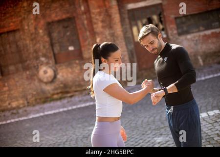 Sporty young woman checking results after jogging with her personal trainer Stock Photo