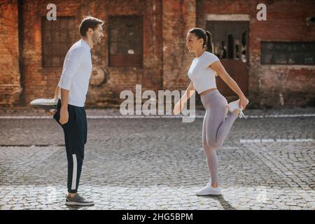Sporty young woman doing stretching exercise after jogging with her personal trainer Stock Photo