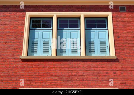 Light blue wooden windows on red shiny brick wall, wide panorama of masonry, bricklaying. Stock Photo